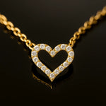 Vergoldete Herz-Halskette mit funkelnden Zirkonia, liegend auf schwarzem, reflektierendem Untergrund – Close-up Produktfoto