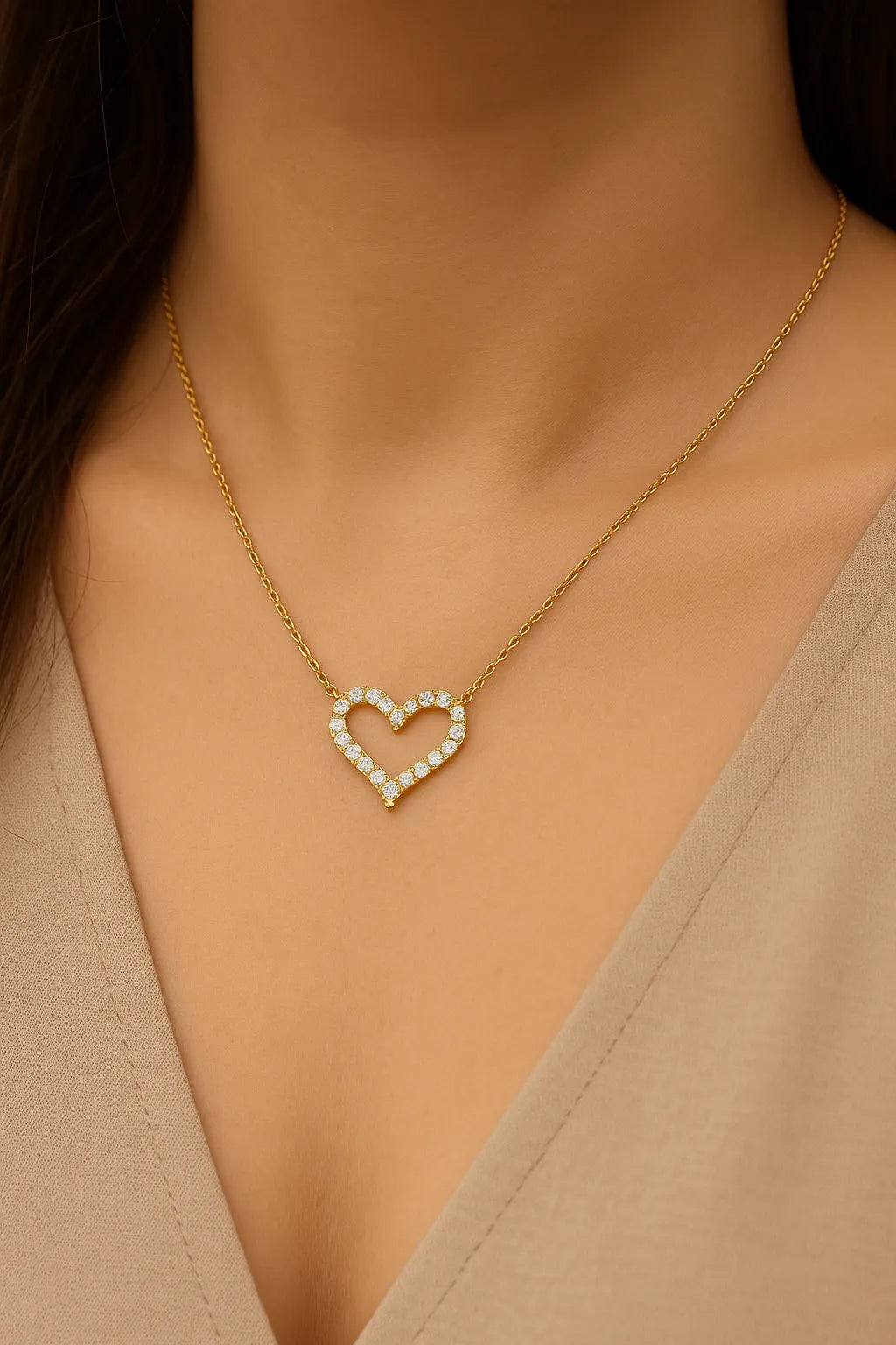 "Goldene Halskette mit funkelndem Herzanhänger aus Zirkonia, getragen an einem femininen Dekolleté mit beigefarbenem V-Ausschnitt – eleganter, romantischer Damenschmuck als Geschenk für Valentinstag oder Jahrestag."