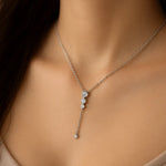 Silberne Y-Halskette mit kleinen Zirkonia, getragen am Hals einer Frau. Der filigrane Anhänger mit vier runden Steinen fällt elegant ins Dekolleté und wirkt feminin und edel.