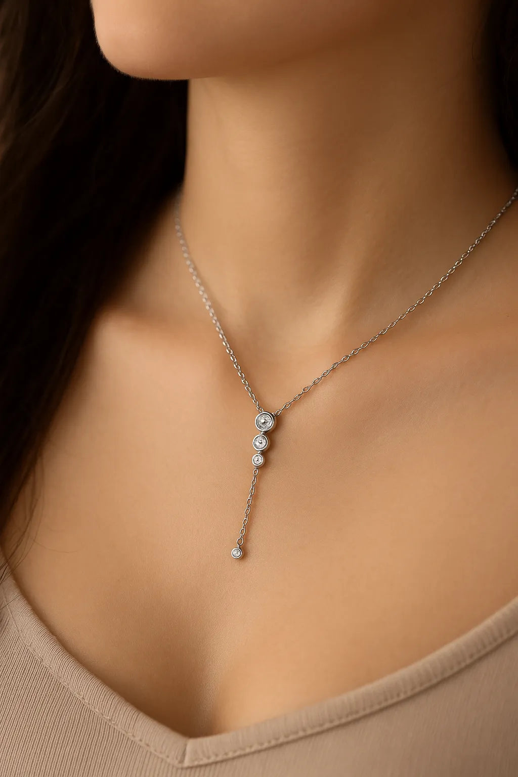 Silberne Y-Halskette mit kleinen Zirkonia, getragen am Hals einer Frau. Der filigrane Anhänger mit vier runden Steinen fällt elegant ins Dekolleté und wirkt feminin und edel.