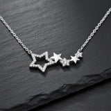Damen Halskette aus 925 Sterling Silber mit mehreren zusammenhängenden Sternanhängern, teils pavé mit klaren Zirkonia besetzt, edel präsentiert auf dunklem Schieferhintergrund.