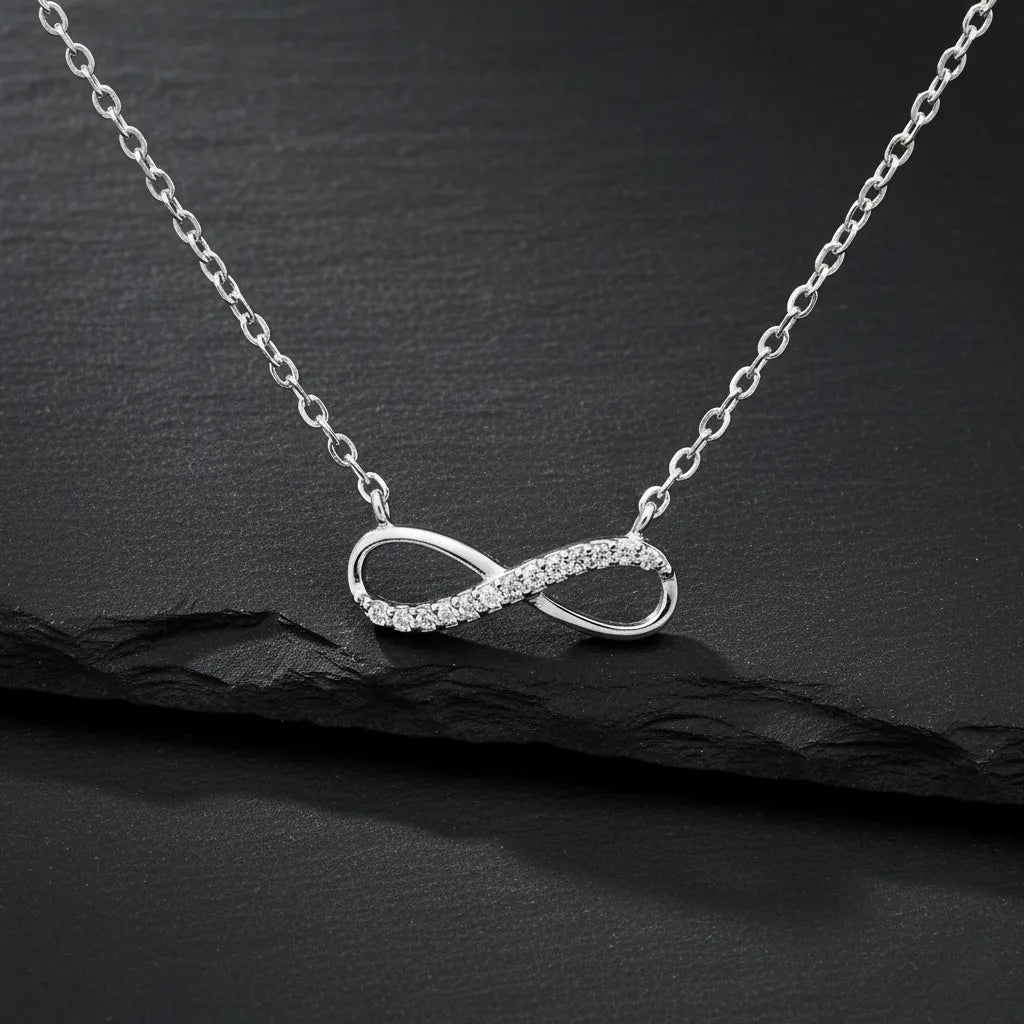 Feine Damen Halskette aus 925 Sterling Silber mit Infinity-Anhänger, teilweise besetzt mit klar funkelnden Zirkonia-Steinen, edel präsentiert auf schwarzem Stein-Hintergrund.