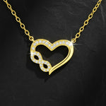 Vergoldete Damen Halskette mit offenem Herz- und Unendlichkeitssymbol, beide besetzt mit funkelnden Zirkonia-Steinen, edel präsentiert auf schwarzem Schieferhintergrund.