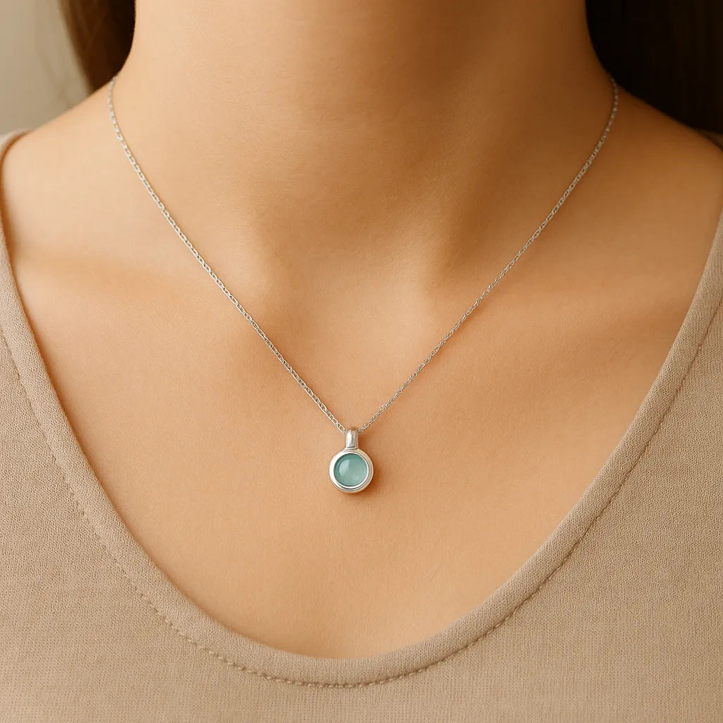 Frau trägt eine feine Silberkette mit rundem Anhänger aus Aqua Chalcedon Cabochon – eleganter, minimalistischer Schmuck mit sanft schimmerndem Edelstein in zartem Blaugrün