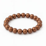 Braunes Perlenarmband aus glänzenden, gleichmäßig runden Perlen, aufgezogen auf elastischem Band vor reinweißem Hintergrund.