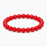 Rotes Perlenarmband aus glänzenden, runden Perlen auf elastischem Band, kreisförmig angeordnet vor reinweißem Hintergrund.