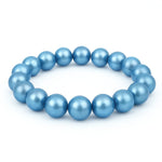 Elastisches Armband aus runden, glänzenden Perlen in schimmerndem Hellblau auf weißem Hintergrund.