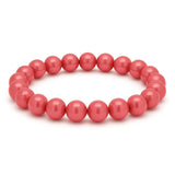 Lachsfarbenes Perlenarmband aus glänzenden, runden Perlen auf elastischem Band, kreisförmig angeordnet vor weißem Hintergrund.