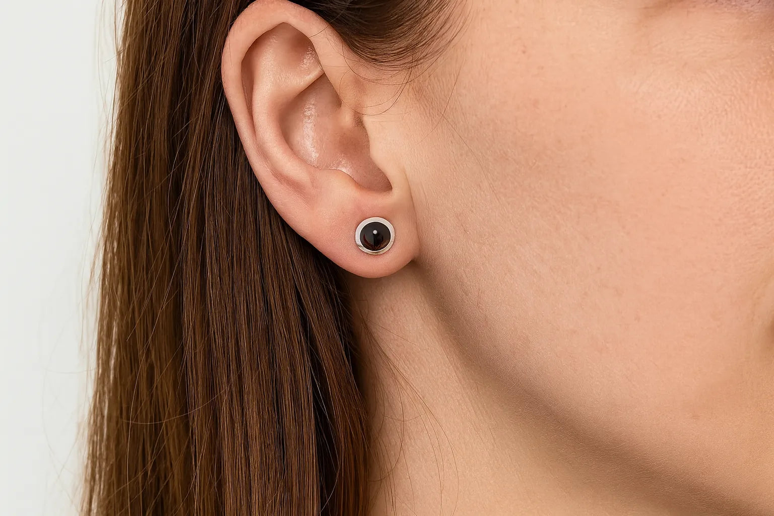 Nahaufnahme eines Ohrs mit einem eleganten Ohrstecker aus 925er Sterlingsilber, besetzt mit einem runden, facettierten Rauchquarz in warmem Braunton. Der Stein reflektiert das Licht dezent und verleiht dem Schmuckstück eine edle, natürliche Ausstrahlung.