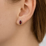 Nahaufnahme eines Ohrs mit einem eleganten Ohrstecker aus Sterlingsilber, besetzt mit einem marquisförmigen, tiefroten Granatstein in glänzender Fassung. Der Schmuck verleiht dem Look eine edle und zugleich moderne Note.