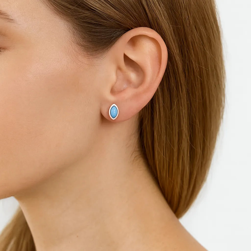 Nahaufnahme eines Ohrs mit einem eleganten Ohrstecker in Marquiseform aus 925er Sterlingsilber, besetzt mit einem himmelblauen Larimar-Cabochon. Der sanft glänzende Stein verleiht dem Ohrschmuck eine frische, edle Ausstrahlung.