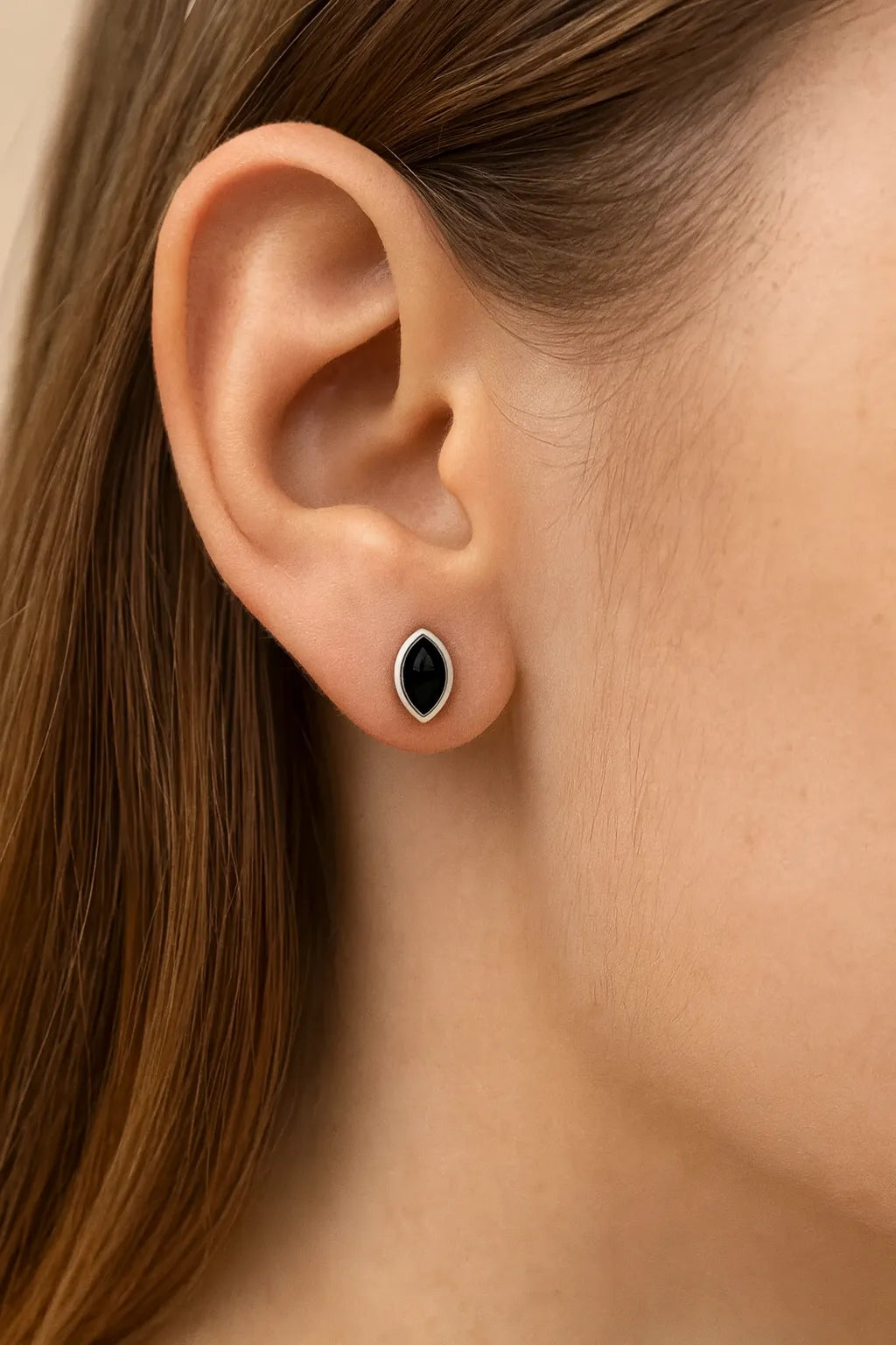 **Alt-Text:**
Nahaufnahme eines Ohrs mit einem eleganten Ohrstecker aus Sterlingsilber, besetzt mit einem tropfenförmigen, schwarzen Onyx-Cabochon in glatter Fassung. Der glänzende Stein verleiht dem Schmuckstück einen klassischen und zugleich modernen Look.