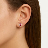 Nahaufnahme eines weiblichen Ohrs mit einem eleganten Ohrstecker aus Sterlingsilber, gefasst mit einem ovalen Rubin-Cabochon in intensivem Rot. Der Edelstein glänzt dezent und verleiht dem Ohrschmuck eine edle und feminine Ausstrahlung.