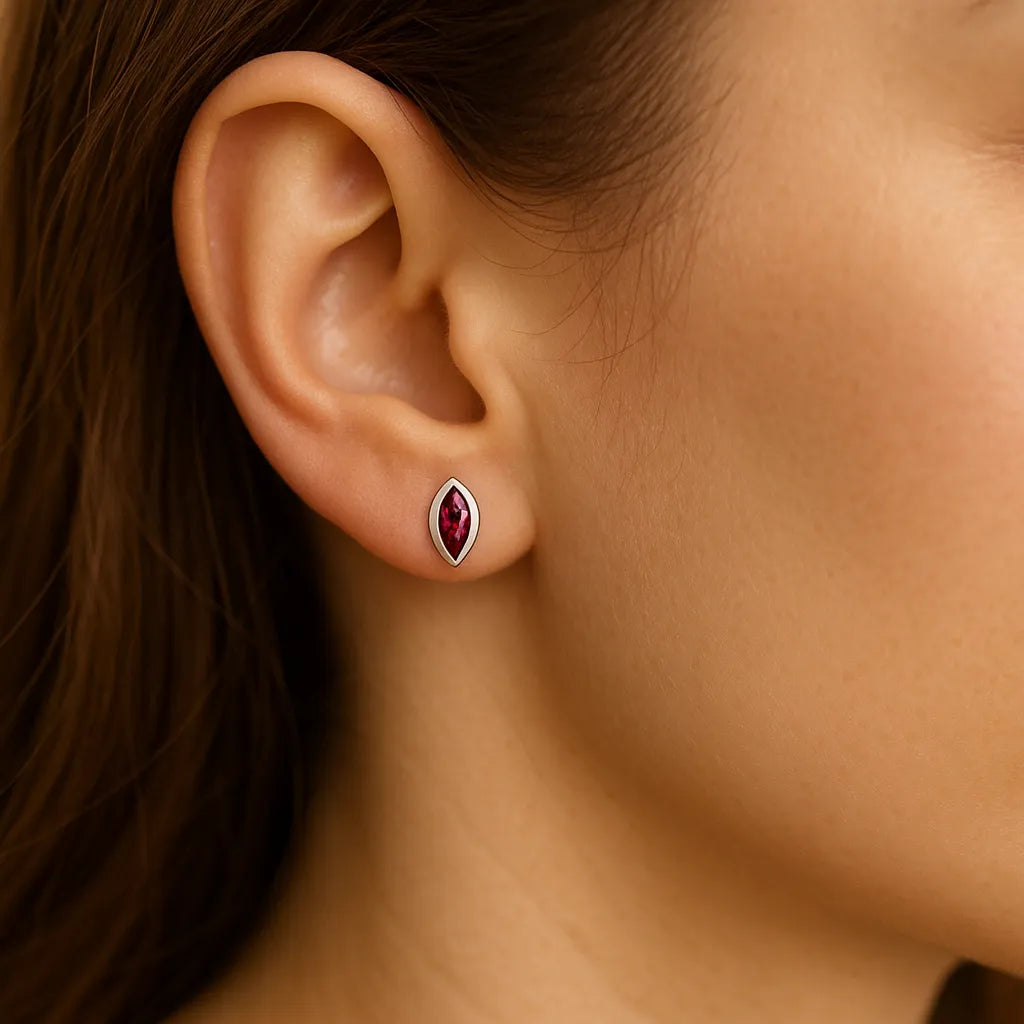 Nahaufnahme eines Ohrs mit einem eleganten Ohrstecker aus Sterlingsilber in Markis-Form, gefasst mit einem funkelnden pink-roten Turmalin. Der Ohrstecker wirkt zart und edel und betont den femininen Stil der Trägerin.
