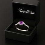 Silberring mit 4 mm violettem Amethyst in offener schwarzen Schmuckschachtel mit Novellara Logo im Deckel, edles Schmuck Geschenk und Produktdarstellung.