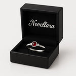 Eleganter Damenring aus Sterling Silber mit kleinem rundem Granat-Cabochon (4 mm) in Zargenfassung, präsentiert in geöffneter schwarzer Schmuckbox mit Novellara Logo im Deckel – hochwertiger Silberring mit rotem Edelstein als Geschenkidee für Frauen.