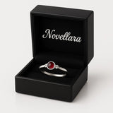 Eleganter Damenring aus Sterling Silber mit kleinem rundem Granat-Cabochon (4 mm) in Zargenfassung, präsentiert in geöffneter schwarzer Schmuckbox mit Novellara Logo im Deckel – hochwertiger Silberring mit rotem Edelstein als Geschenkidee für Frauen.