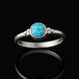 Sterlingsilber-Ring mit türkisem Larimarstein, seitlich fotografiert auf schwarzem glänzenden Spiegel-Untergrund mit deutlicher Reflexion, edles Produktfoto für handgefertigten Damenschmuck.