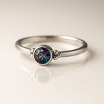 Zarter Damenring aus poliertem Silber mit rundem facettiertem Mystic Topas in Grün-Lila Schimmer, Zargenfassung und Kugeldetails – eleganter Silberring mit Edelstein auf hellem Hintergrund