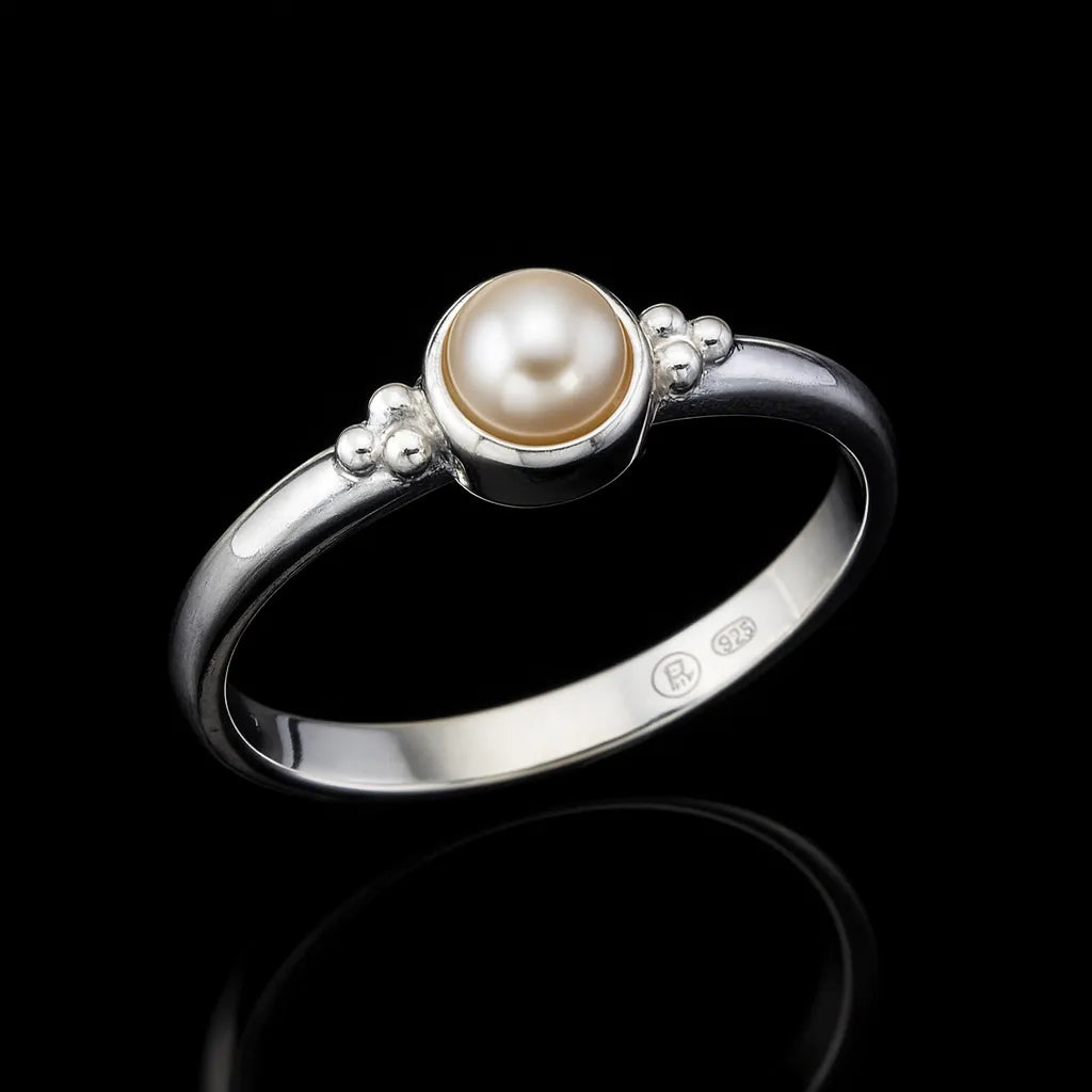 Eleganter 925-Silberring mit champagnerfarbener Perle in runder Fassung, seitliche Nahaufnahme auf schwarzem hochglänzendem Spiegeluntergrund mit starker Reflexion, edler Perlenschmuck für Damen