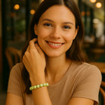 Halbportrait einer freundlich lächelnden Frau in einem Café, die ein elegantes 3D Wonderperlen Armband in zartem Pastellgrün am rechten Handgelenk trägt