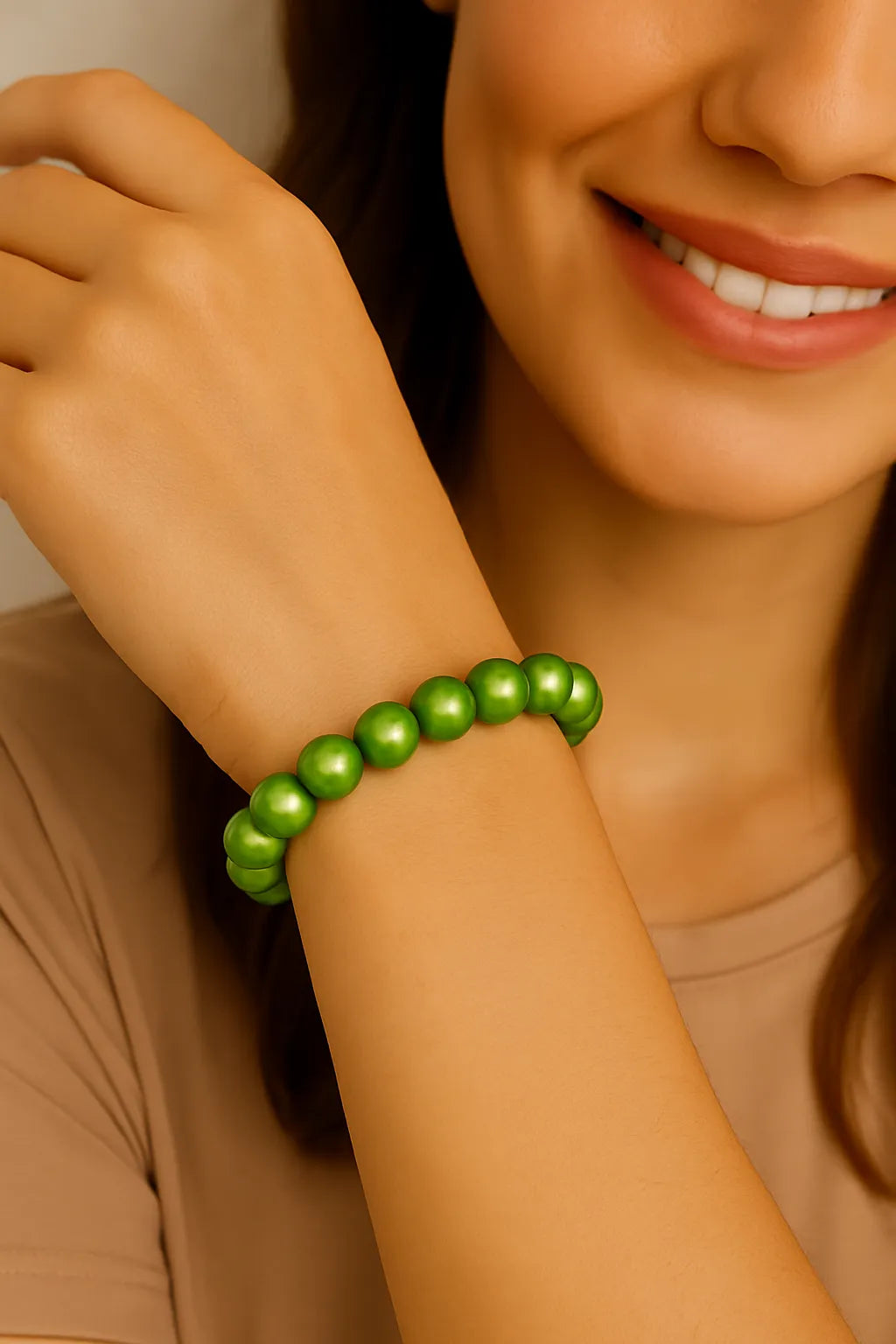 Nahaufnahme einer lächelnden Frau mit hellem Teint, die ein elastisches Armband aus glänzenden, hellgrünen Perlen am rechten Handgelenk trägt.