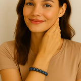 Eine junge Frau mit mittellangen braunen Haaren trägt ein elastisches Armband aus dunkelblauen, glänzenden Perlen am Handgelenk