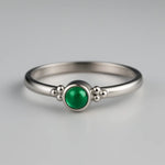 Eleganter Damenring aus 925 Sterling Silber mit rundem Smaragd-Cabochon in leuchtendem Grün, gefasst in einer Zargenfassung mit feinen Silberkügelchen, edel inszeniert im Studio auf hellem Hintergrund als hochwertiger Edelsteinschmuck.