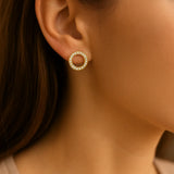 Vergoldeter runder Ohrstecker mit klar funkelnden Zirkonia-Steinen, getragen am Ohr einer Frau; eleganter, zeitloser Kreis-Ohrring im minimalistischen Stil.
