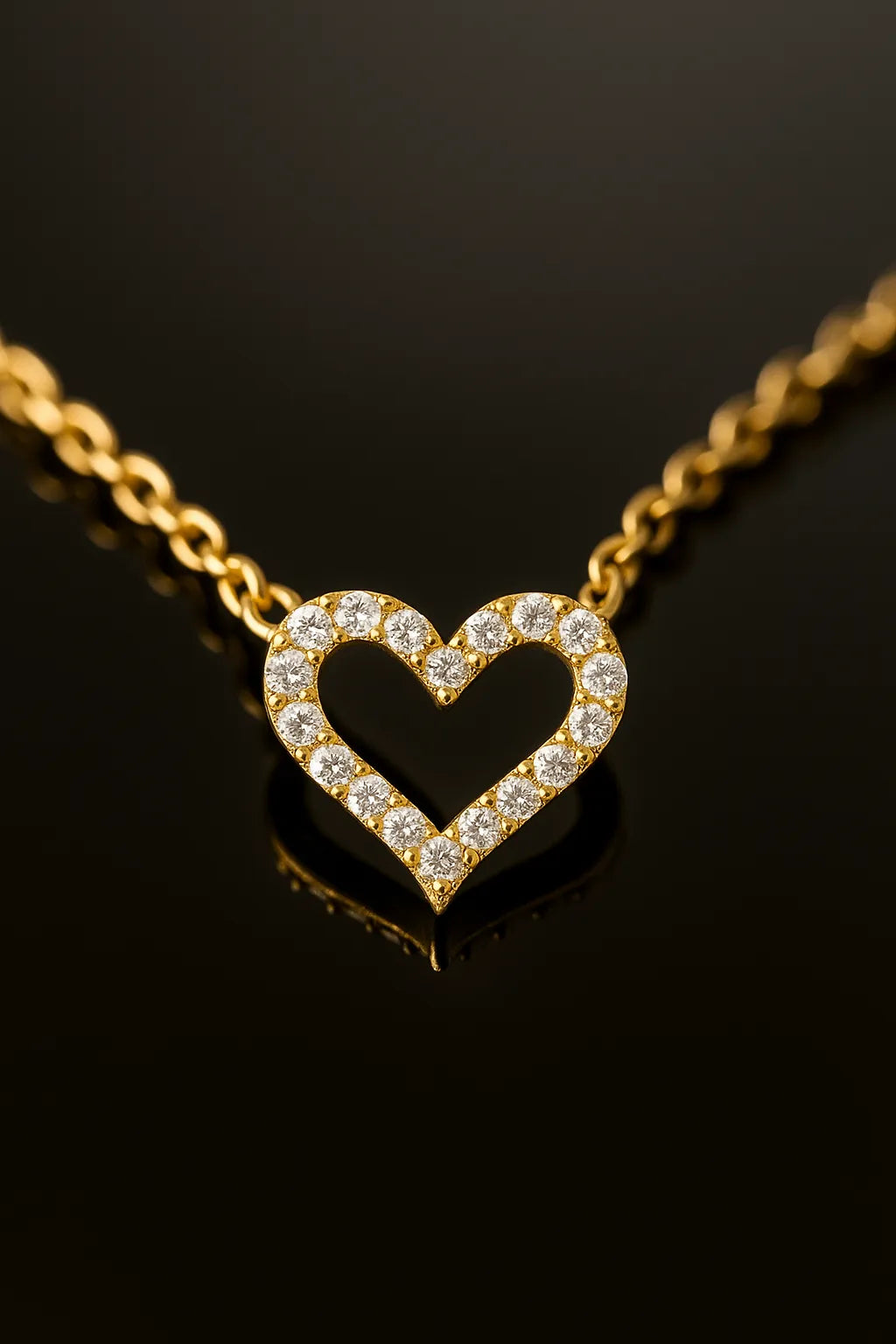 Vergoldete Herz-Halskette mit funkelnden Zirkonia, liegend auf schwarzem, reflektierendem Untergrund – Close-up Produktfoto
