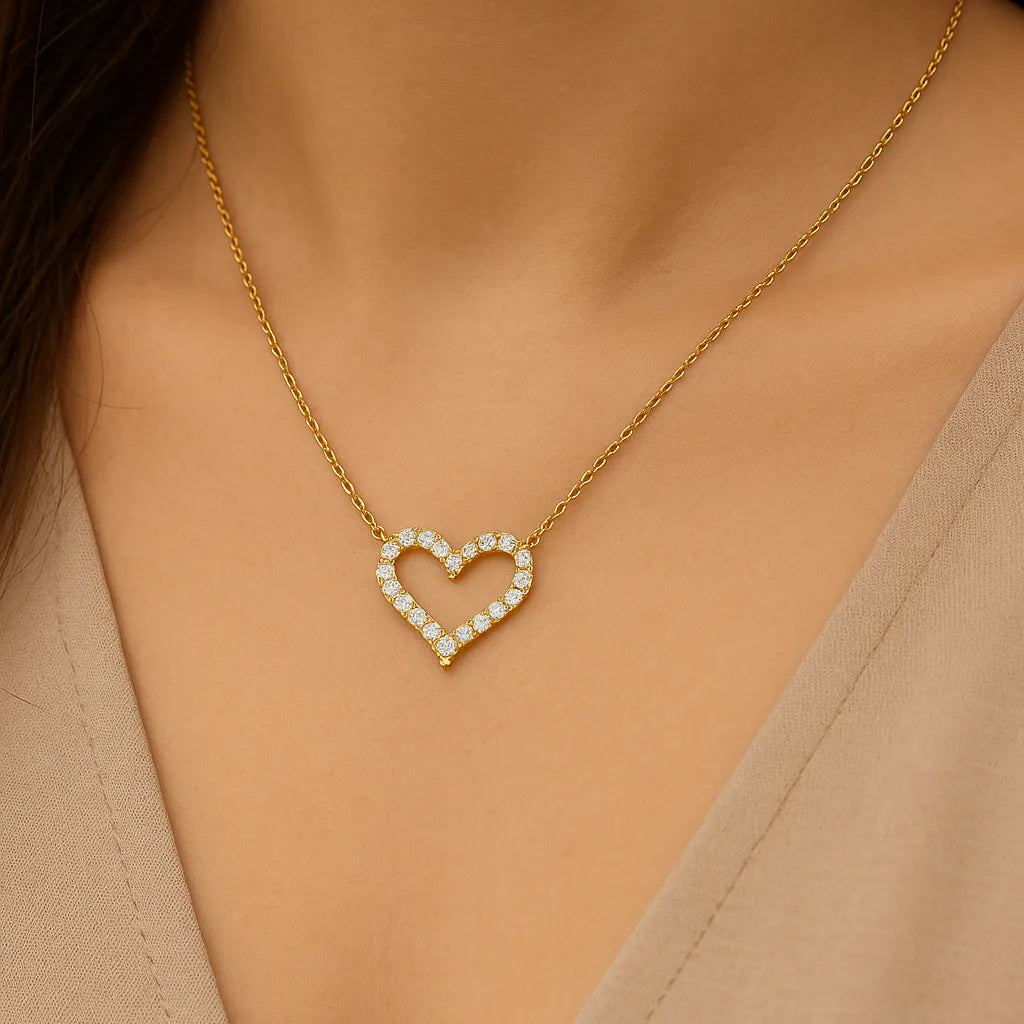 "Goldene Halskette mit funkelndem Herzanhänger aus Zirkonia, getragen an einem femininen Dekolleté mit beigefarbenem V-Ausschnitt – eleganter, romantischer Damenschmuck als Geschenk für Valentinstag oder Jahrestag."
