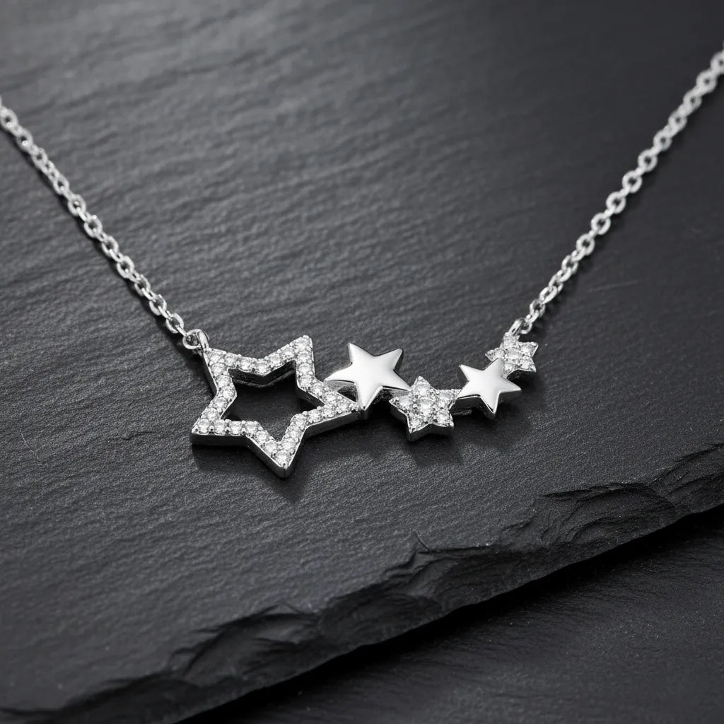 Damen Halskette aus 925 Sterling Silber mit mehreren zusammenhängenden Sternanhängern, teils pavé mit klaren Zirkonia besetzt, edel präsentiert auf dunklem Schieferhintergrund.
