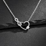 Feine Damen Halskette aus 925 Sterling Silber mit Herz-und-Unendlichkeitsanhänger, besetzt mit funkelnden Zirkonia und rundem Solitärstein, edel inszeniert auf schwarzem Schiefer.

