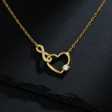 Vergoldete Damen Halskette mit offenem Herz- und Infinity-Anhänger, besetzt mit klar funkelnden Zirkonia und rundem Solitärstein, edel präsentiert auf dunklem Schieferhintergrund.
