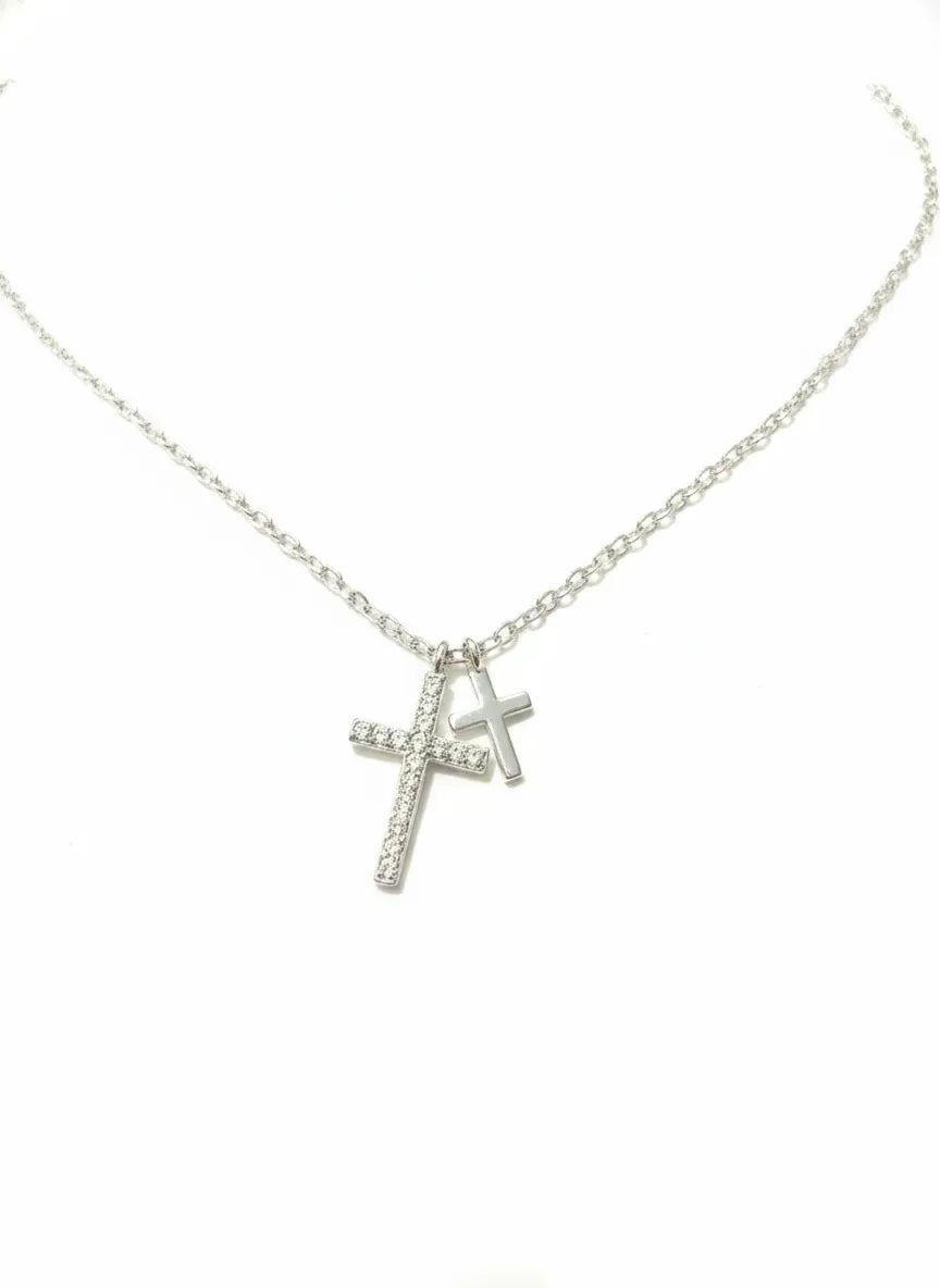 Silberne Halskette mit zwei Kreuzanhängern, großer Kreuzanhänger mit funkelnden Zirkonia, kleiner glatt poliert, vor weißem Hintergrund – Damen Schmuck 925 Sterling Silber.