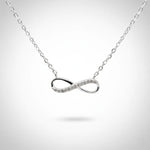 Feine Damen Halskette aus 925 Sterling Silber mit elegantem Infinity-Anhänger, teilweise besetzt mit funkelnden klaren Zirkonia-Steinen, freigestellt vor hellem Studiohintergrund.
