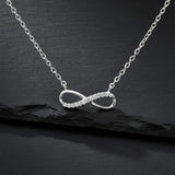 Feine Damen Halskette aus 925 Sterling Silber mit Infinity-Anhänger, teilweise besetzt mit klar funkelnden Zirkonia-Steinen, edel präsentiert auf schwarzem Stein-Hintergrund.