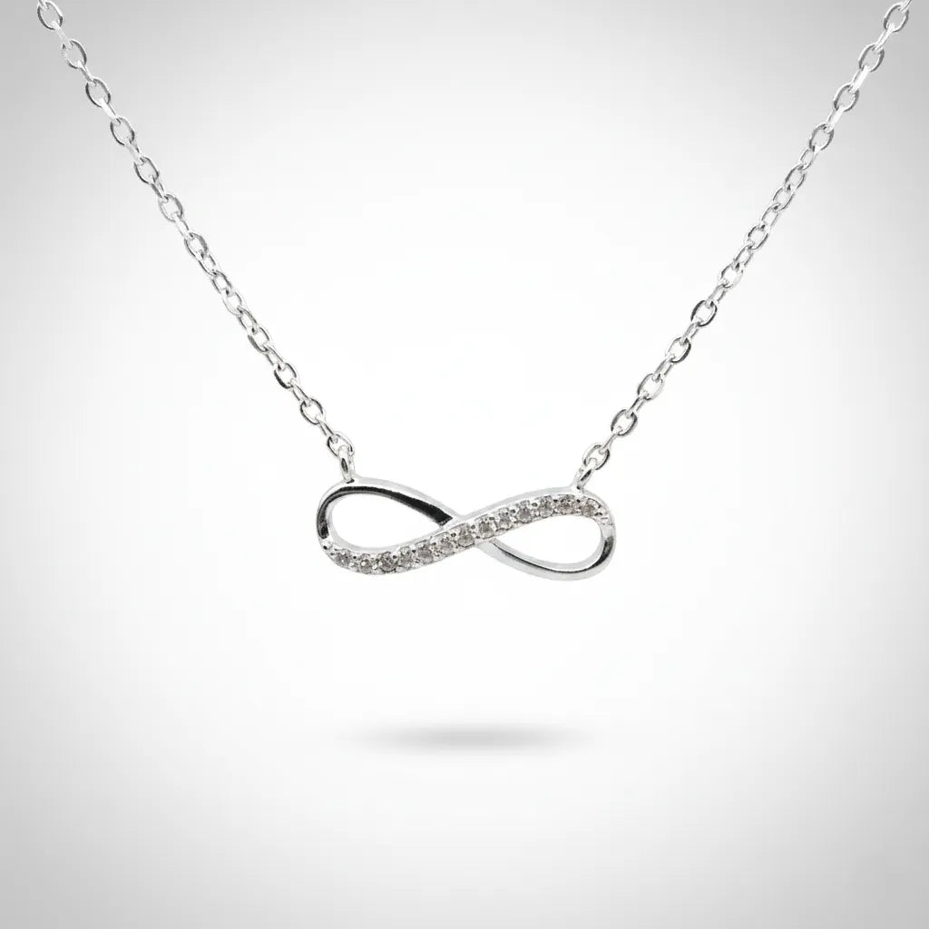 Feine Damen Halskette aus 925 Sterling Silber mit elegantem Infinity-Anhänger, teilweise besetzt mit funkelnden klaren Zirkonia-Steinen, freigestellt vor hellem Studiohintergrund.
