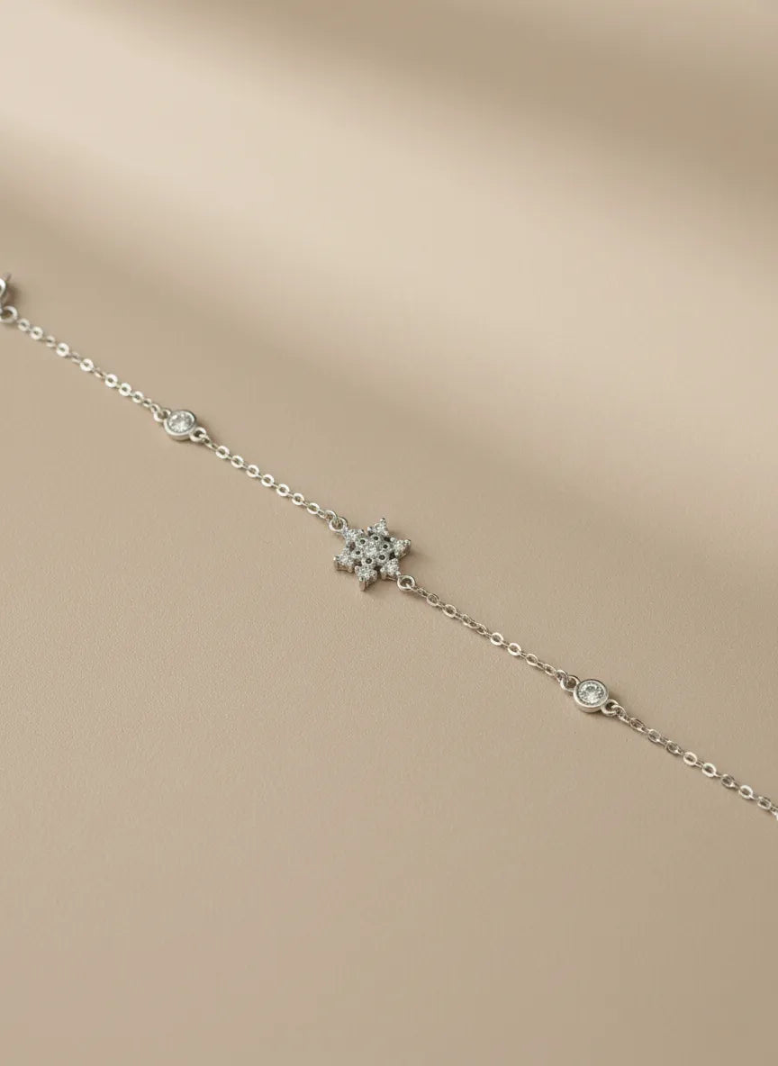 Silberne Armkette liegend mit funkelndem Schneeflocken-Design