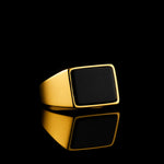 Goldener Herren-Siegelring mit schwarzem Achat, low-key Aufnahme auf schwarzem Hintergrund mit Spiegelung; edles IPG-Finish, dramatisches Licht, luxuriöser Premium-Look.
