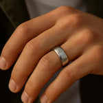 Herrenring Edelstahl silber, 7 mm breit, poliert – getragen am Ringfinger; Nahaufnahme im warmen Fensterlicht, natürliche Hauttöne, moderner Look.
