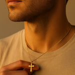 Herren Halskette aus vergoldetem Edelstahl mit Kreuzanhänger, getragen am Hals eines Mannes im Golden-Hour-Licht; feine Ankerkette, minimalistischer Stil.