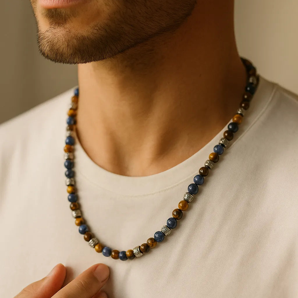 Herren Halskette mit Sodalith- und Tigerauge-Perlen, Edelstahl-Spacer; getragen am Hals eines Mannes im warmen Fensterlicht, Nahaufnahme mit neutralem Hintergrund.
