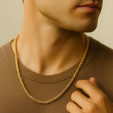 Herren Königskette goldfarben 4 mm, aus Edelstahl, getragen am Hals eines Mannes; Nahaufnahme im warmen Fensterlicht, moderner Premium-Look.
