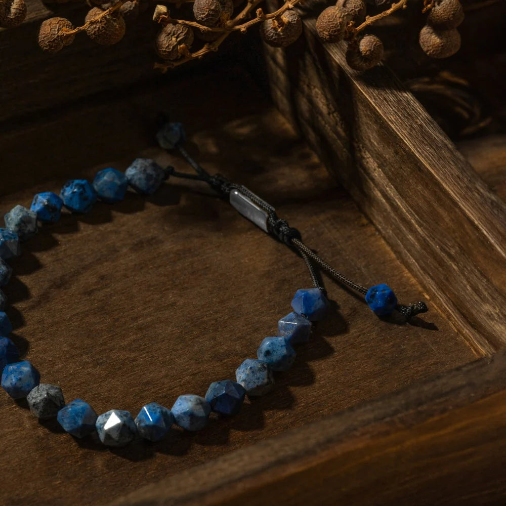 SON Herrenarmband mit facettierten 8 mm Sodalit-Perlen, Edelstahl-Detail und schwarzer Makramé-Schnur auf dunklem Holz