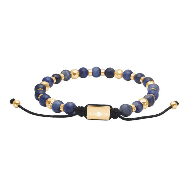 Das Bild zeigt ein verstellbares Unisex-Perlenarmband aus mattem blauem Sodalith mit silbernen oder goldfarbenen Edelstahlelementen und schwarzer Textilkordel für stilbewusste Damen und Herren.