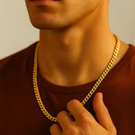 Herren Panzerkette vergoldeter Edelstahl, getragen am Hals eines Mannes; Nahaufnahme mit Hand am Hals, warmes Fensterlicht, neutraler Hintergrund, moderner Look.