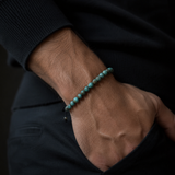 SON Herrenarmband aus 6 mm African-Turquoise-Perlen, markant getragen zu dunklem Strick im maskulinen Premium-Look