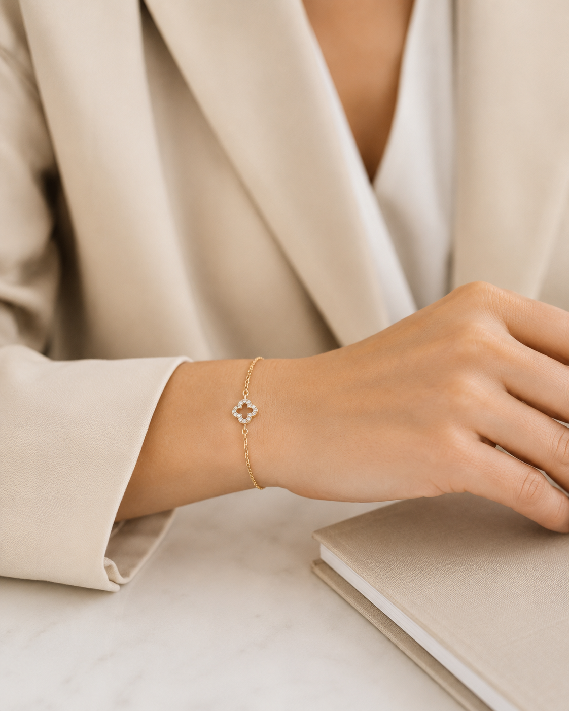PamelaNor Armband aus vergoldetem 925 Silber mit funkelndem Anhänger, stilvoll zu hellem Blazer und Notizbuch getragen.