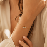 Feminines PamelaNor Armband mit zartem Goldglanz und funkelndem Kleeblatt-Motiv in warmer natürlicher Lichtstimmung.